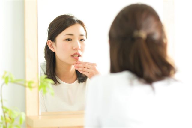 woman-touching-her-mouth-in-the-mirror