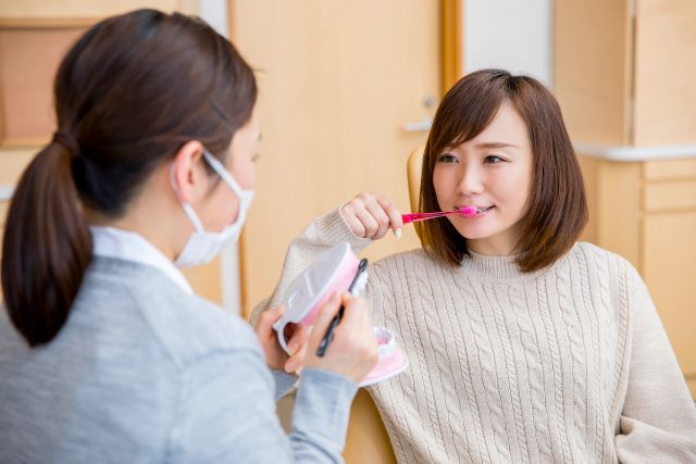 歯磨きをする女性とアドバイスする女性